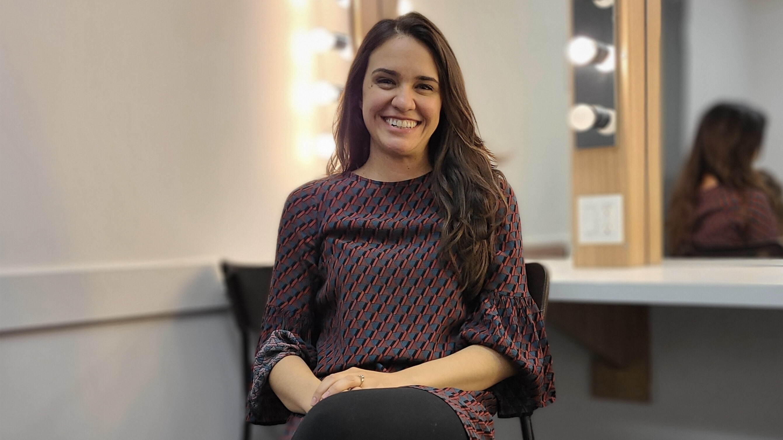 Photo of Emily Lukasik smiling as she sits in her dressing room at Hamilton Family Theatre Cambridge