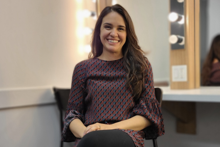 Photo of Emily Lukasik smiling as she sits in her dressing room at Hamilton Family Theatre Cambridge